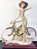 This figurine is a Giuseppe Armani sculpture titled "The Bicycle - Spring"