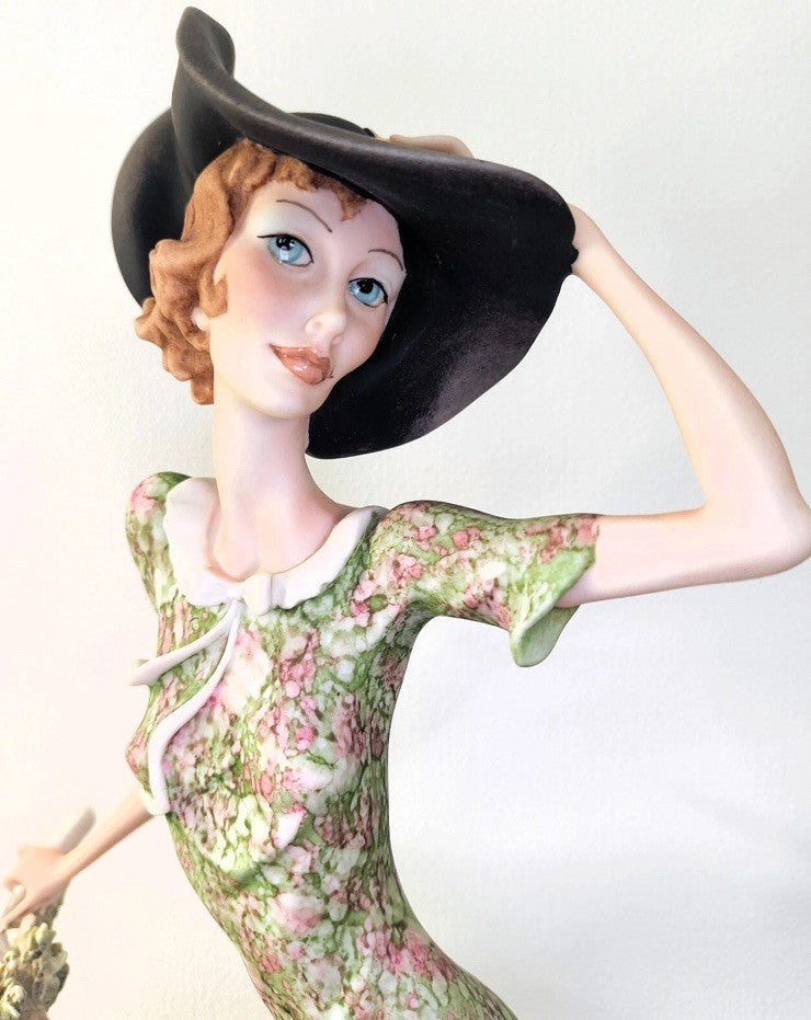 This figurine is a Giuseppe Armani sculpture titled "The Bicycle - Spring"
